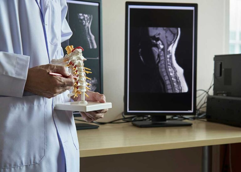 Person performing a guided back mobility exercise on a mat beside a treatment table.